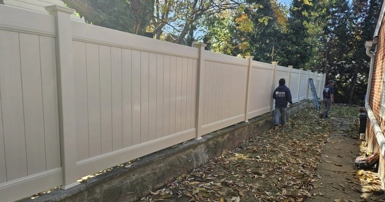 A man is engaged in fence work in a yard, emphasizing compliance with fencing regulations in New York City and New Jersey.