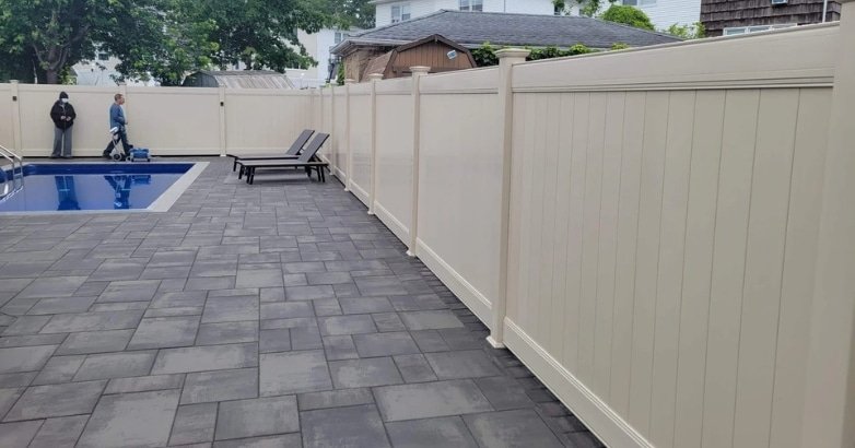 A pool enclosed by a fence and patio, emphasizing the professional constructor and the importance of safety regulations in New York City and New Jersey.