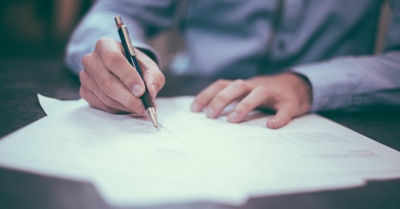 A person writes on paper with a pen, focusing on fencing regulations and permit requirements in New York City and New Jersey.
