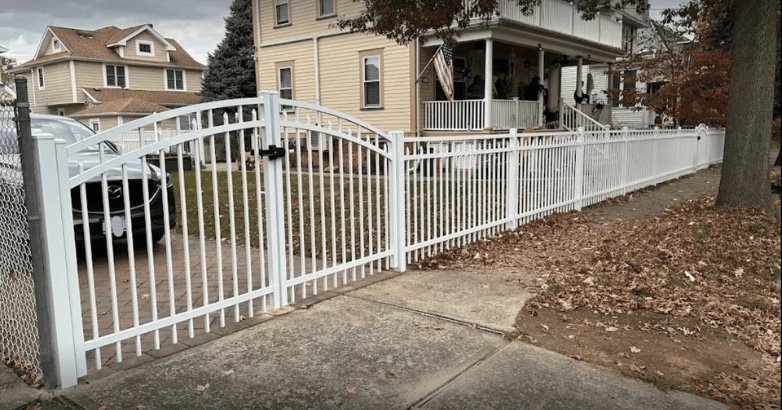 A white fence with a gate stands in front of a house, highlighting custom metal fencing options for urban environments.