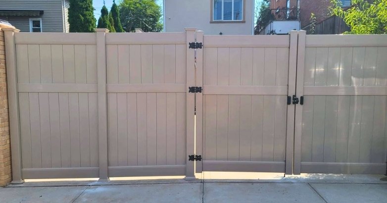 A prominent gate is flanked by a white fence, highlighting choices for selecting a driveway gate for homes.
