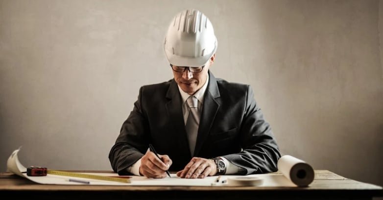 A man in formal attire and a hard hat writes on paper, symbolizing a trusted installer for residential driveway gates.
