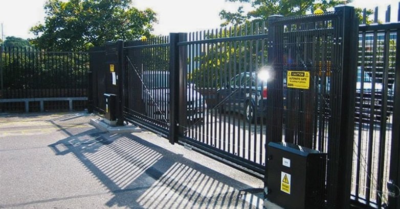 A black gate featuring a yellow sign, symbolizing modern automated gates for businesses and enhancing property aesthetics.