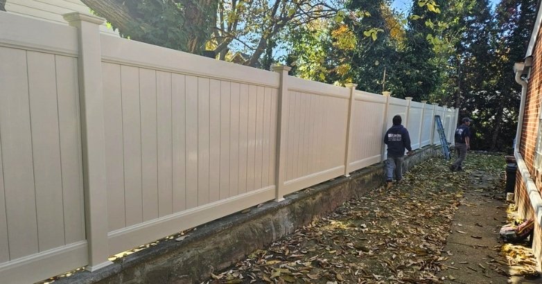 A worker cleans a fence in a residential neighborhood, showcasing low-maintenance fencing options for New Jersey homes