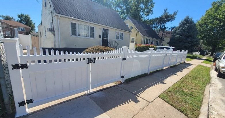 A charming white picket fence in front of a house, showcasing custom fencing for New Jersey homes.