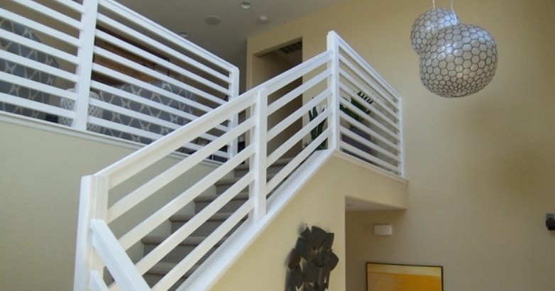  Interior view of a stairway with white railings, horizontal wood slats, and a lamp providing soft lighting.