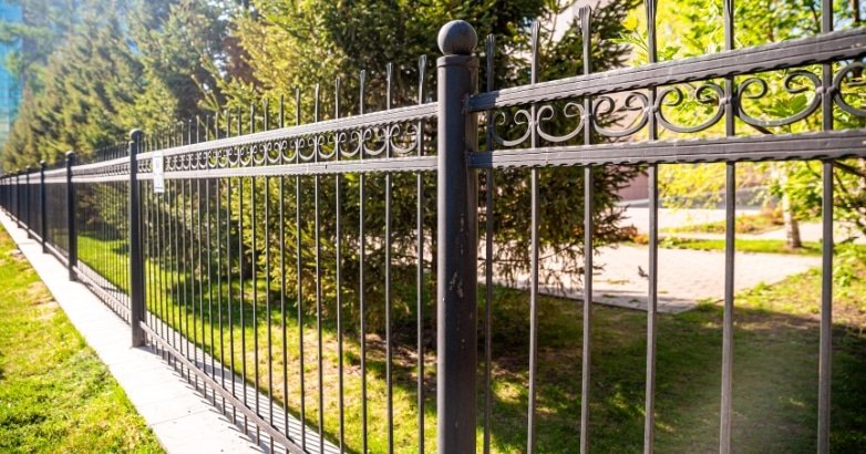 A black wrought iron fence featuring intricate designs, showcasing Five Boroughs Fencing Solutions for commercial properties.