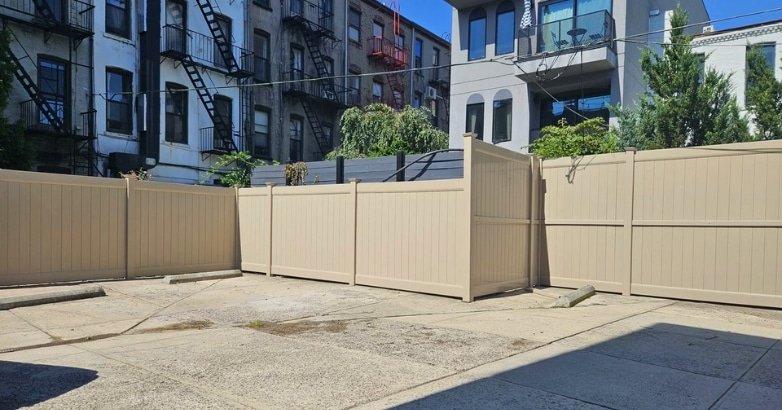 A vinyl fence is positioned in front of a building, highlighting Five Boroughs Fencing Solutions for commercial properties.