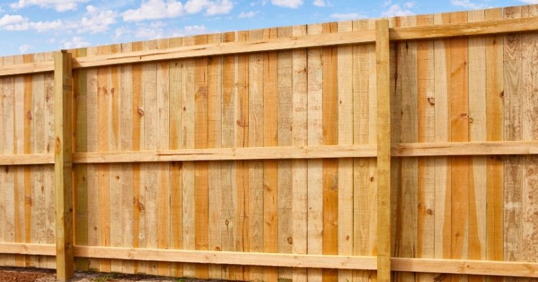 A wooden fence set against a blue sky, illustrating the services of Five Boroughs Fencing Solutions for commercial fencing.