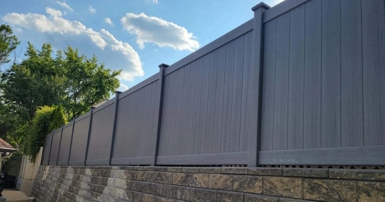 A gray vinyl panel fence designed to reduce noise pollution on residential properties.