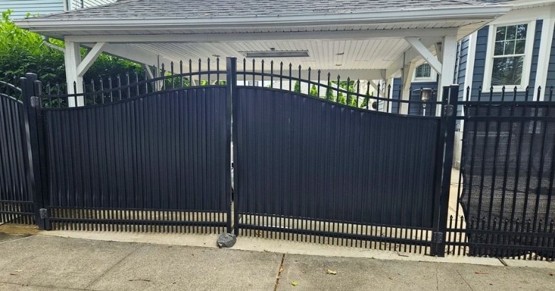 A black wrought iron gate stands elegantly in front of a house, enhancing the property's curb appeal.