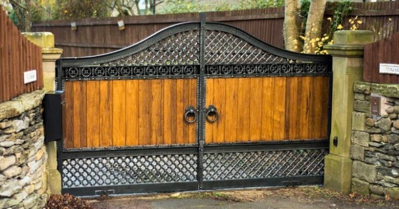 A wooden gate paired with a metal gate, showcasing a stylish mixed material design for residential curb appeal.