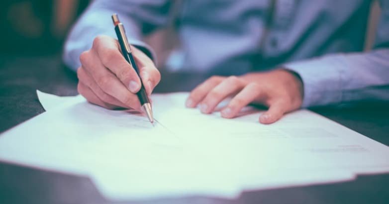 A person writes notes on paper with a pen, focusing on modern and traditional railing styles for home safety compliance.