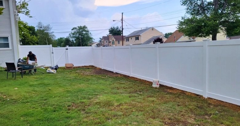 DIY vs Professional Fencing Which Way Should You Go A white fence is being assembled in a backyard, highlighting a difference between DIY vs Professional approach to fencing solutions.