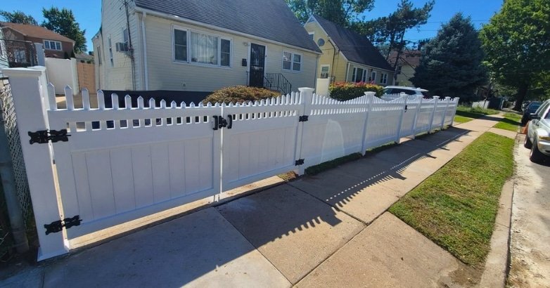 How to Choose the Right Fencing Contractor In The Metro Area Evaluate Materials A white picket fence with a black gate, illustrating a classic fencing option for residential properties.
