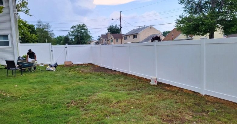 Checklist for Planning a Fencing Project Choose a Trusted Fence Contractor A white fence is under construction in a backyard, emphasizing the importance of choosing a trusted fence contractor.