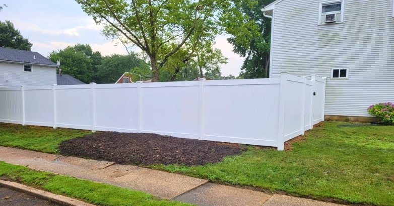 Emergency Fence Repairs From Repairs to New Installations A white fence borders a house, highlighting services for emergency repairs and new fence installations.