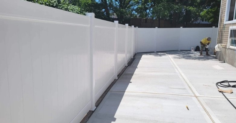 Emergency Fence Repairs Process A white fence is being painted in a backyard, illustrating the process of emergency fence repairs.