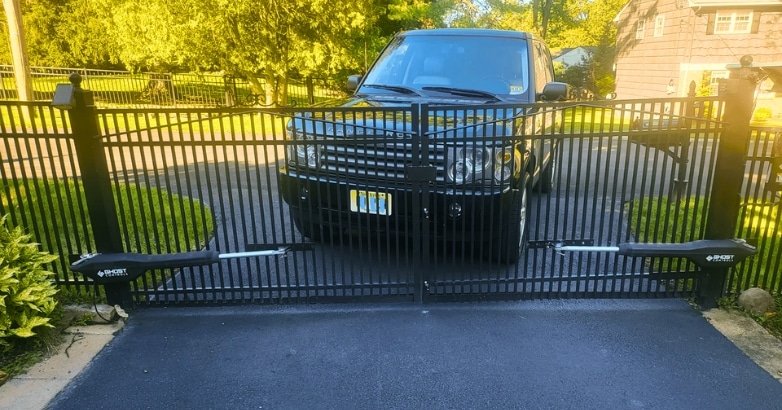 Sloped Driveway Gate Installation Automatic Gate Opener A black SUV is parked before a sloped driveway gate featuring an automatic gate opener installation.