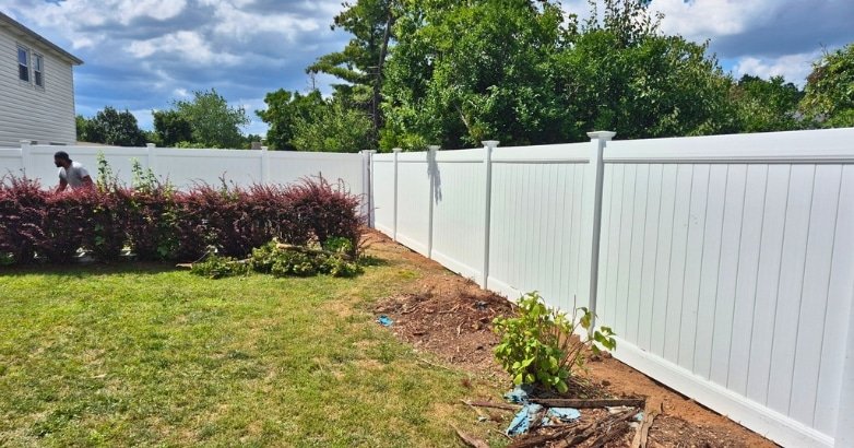 Planning a Budget Friendly Fencing Project Choosing the Right Fencing Company The backyard of a house showcases a white fence, representing a budget-friendly fencing project from Jr Fencing.