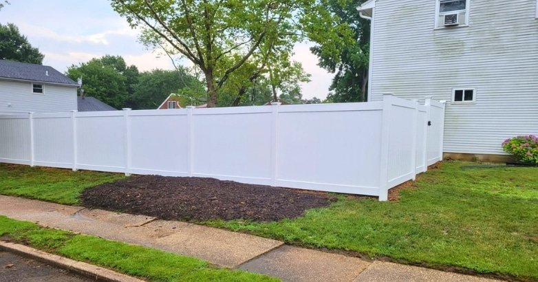 Planning a Budget Friendly Fencing Project Installation Choices A white fence stands in front of a house, illustrating options for a budget-friendly fencing project.
