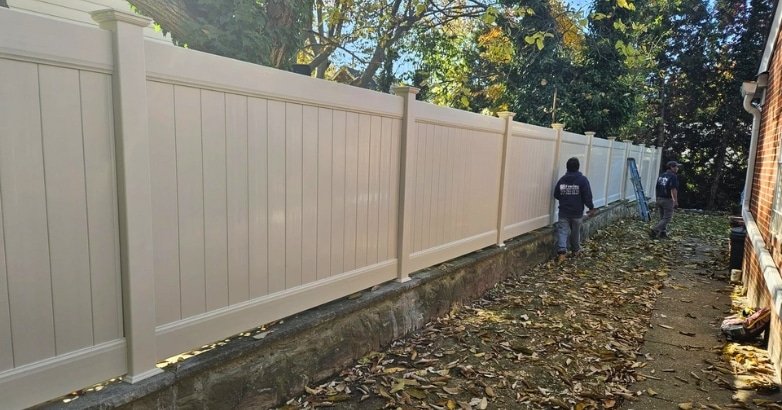 Upgrading Your Old Fence Upgrading the Right Way A man is engaged in upgrading a wooden fence in his yard, emphasizing the importance of proper fence improvement techniques.