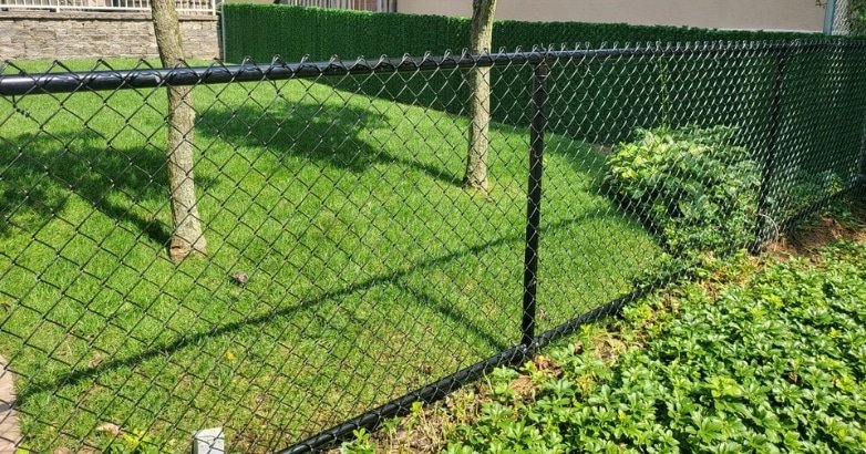 Fencing Solutions for High Traffic Urban Areas Chain Link A sturdy black chain link fence in a yard, suitable for urban environments with heavy foot traffic.