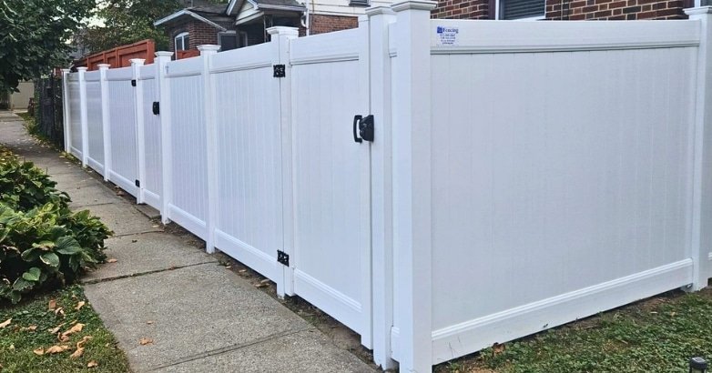 Seasonal Fencing Maintenance in New York Spring A white fence with black trim and a black gate, representing seasonal fencing maintenance in New York during spring.
